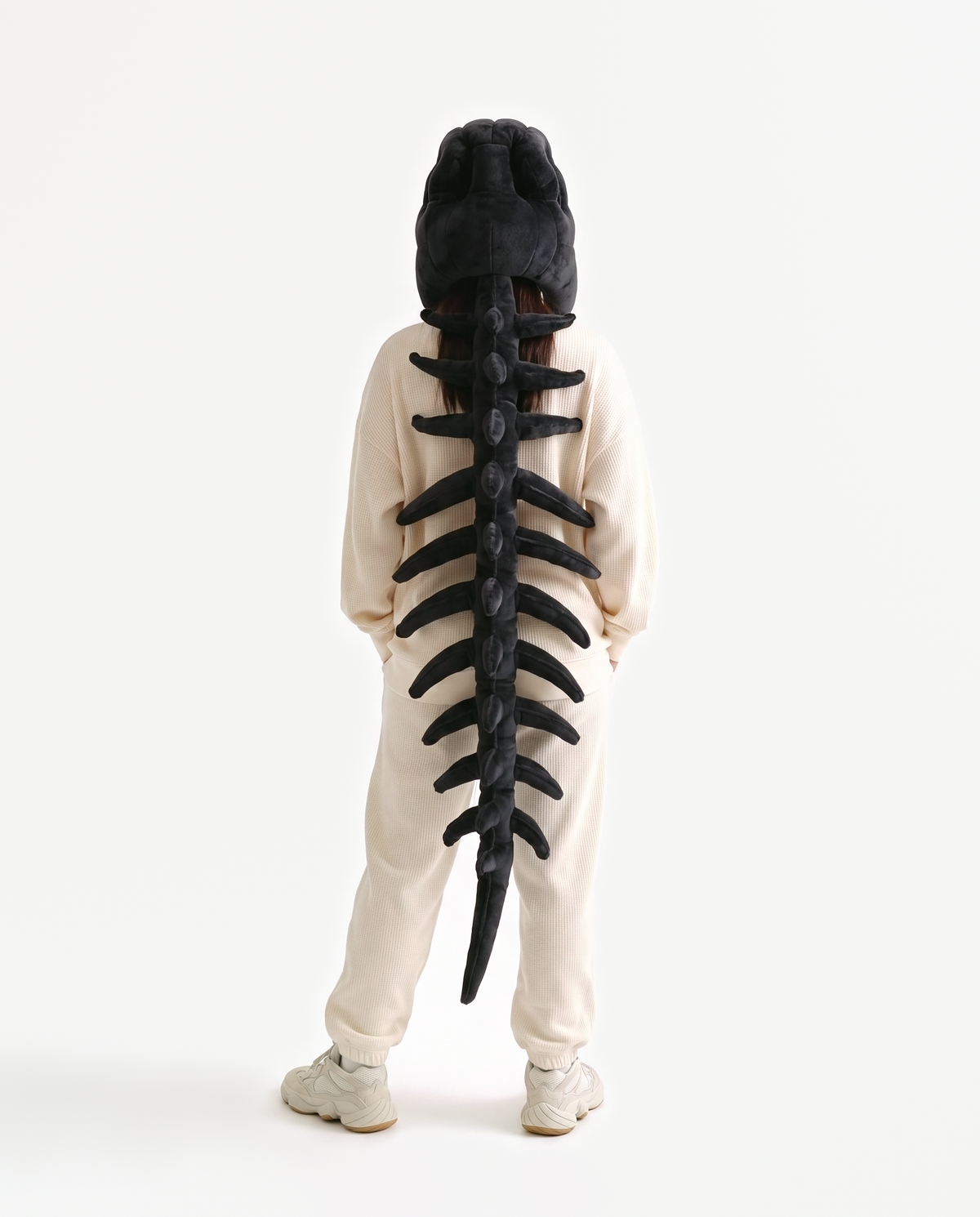 The Dinosaur Skeleton in Black — plush dinosaur skeleton costume seen from behind, spine down the back