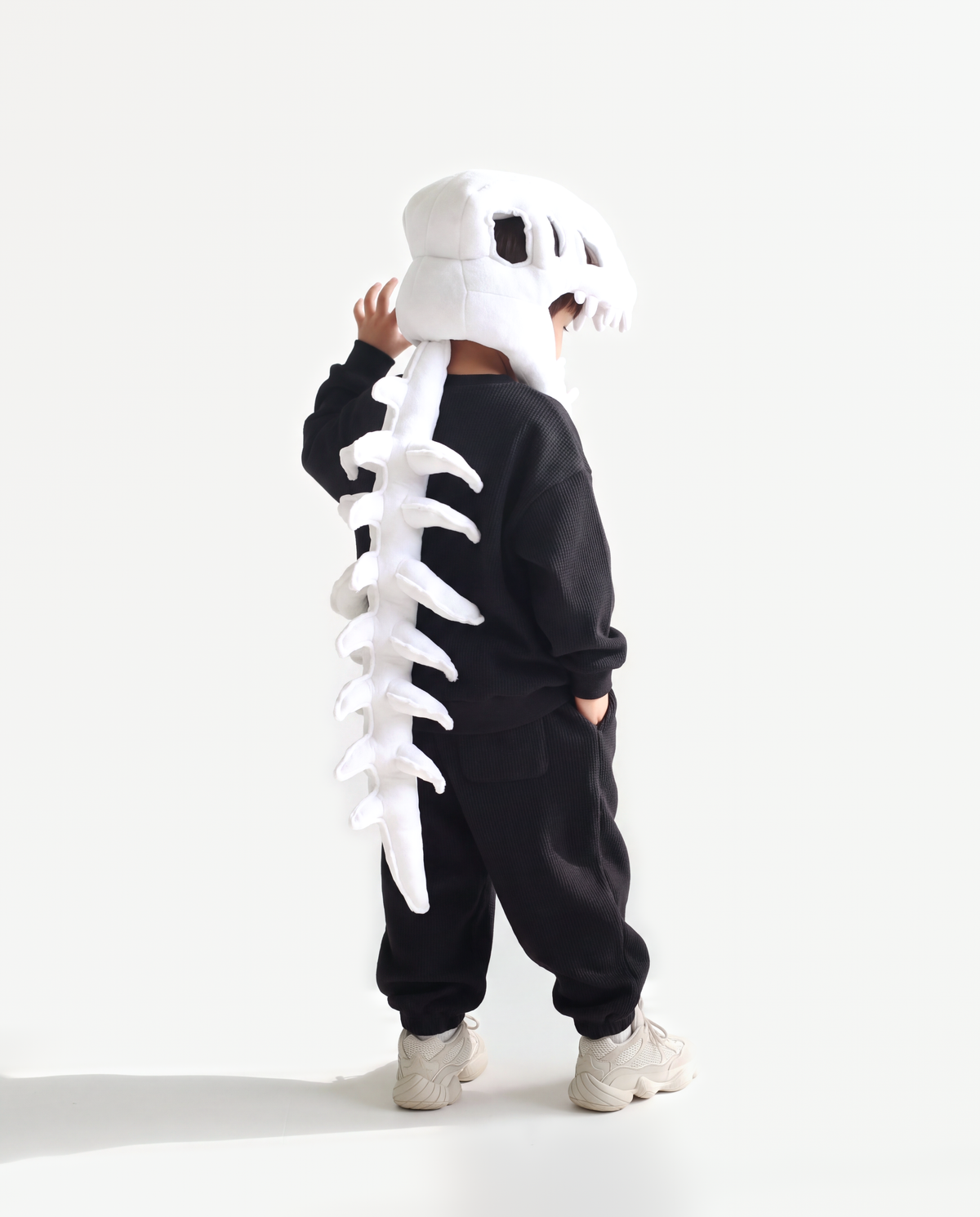 The Dinosaur Skeleton in Bone — plush dinosaur skeleton costume with skull hood and spine, side view