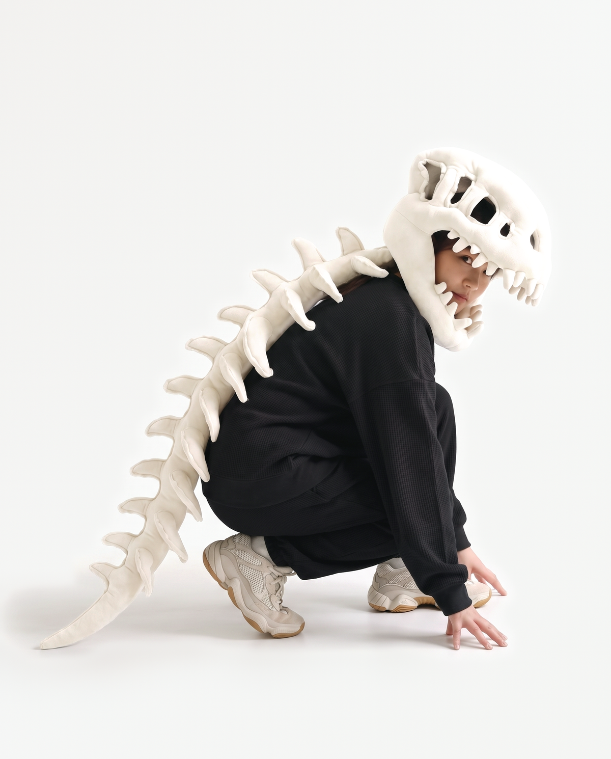 The Dinosaur Skeleton in Bone — plush dinosaur skeleton costume with skull hood and spine, crouching