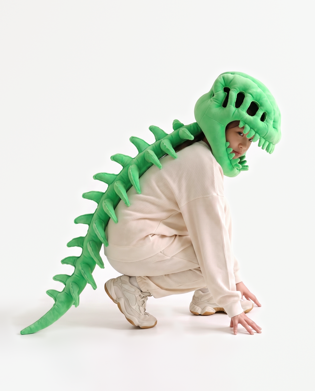 The Dinosaur Skeleton in Green — plush dinosaur skeleton costume with skull hood and spine, crouching