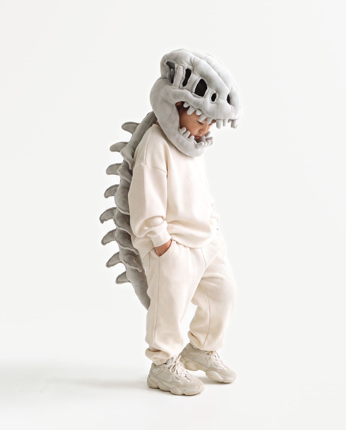 The Dinosaur Skeleton in Grey — plush dinosaur skeleton costume with skull hood and spine, side view