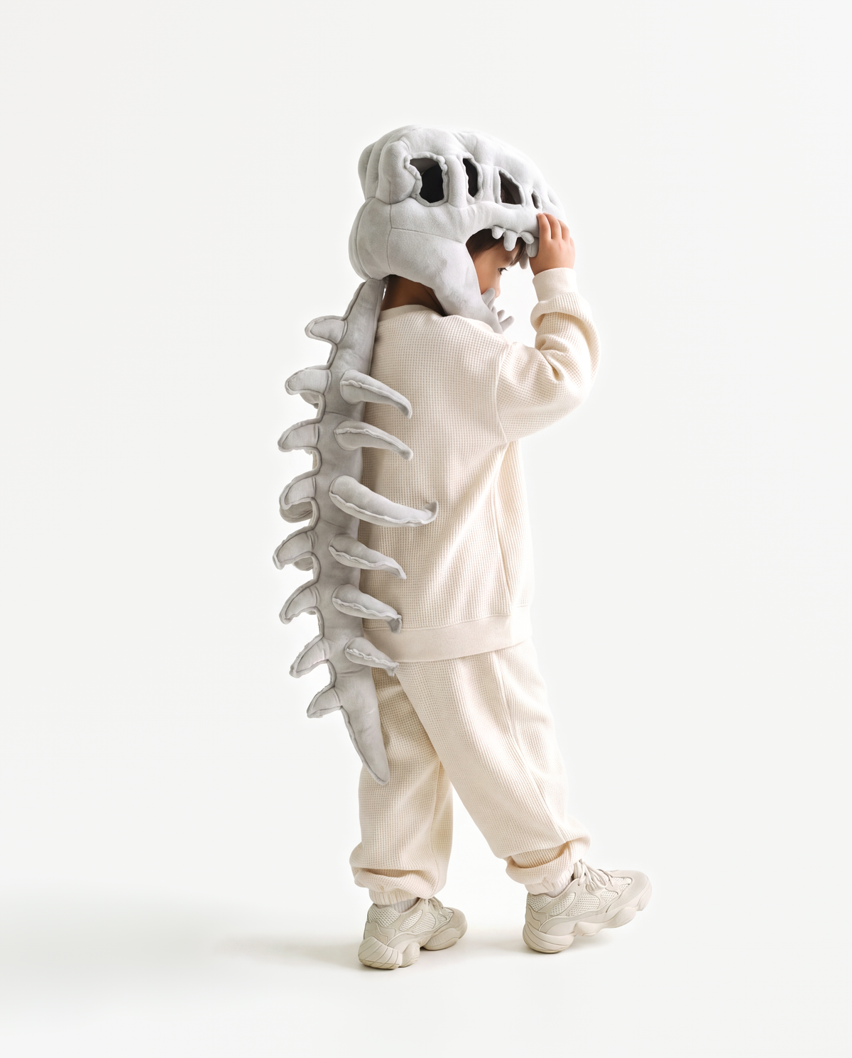 The Dinosaur Skeleton in Grey — plush dinosaur skeleton costume with skull hood and spine, side view