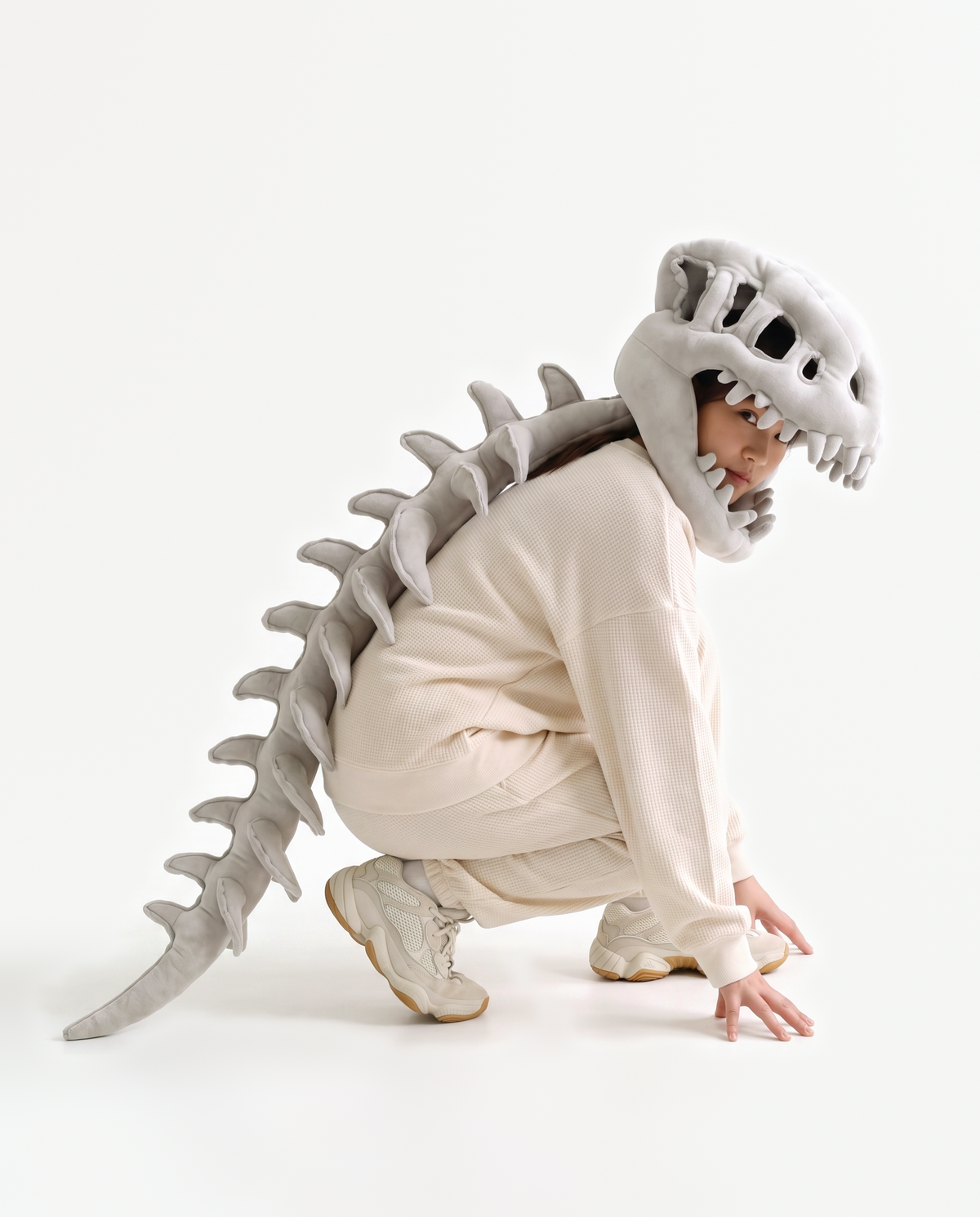 The Dinosaur Skeleton in Grey — plush dinosaur skeleton costume with skull hood and spine, crouching